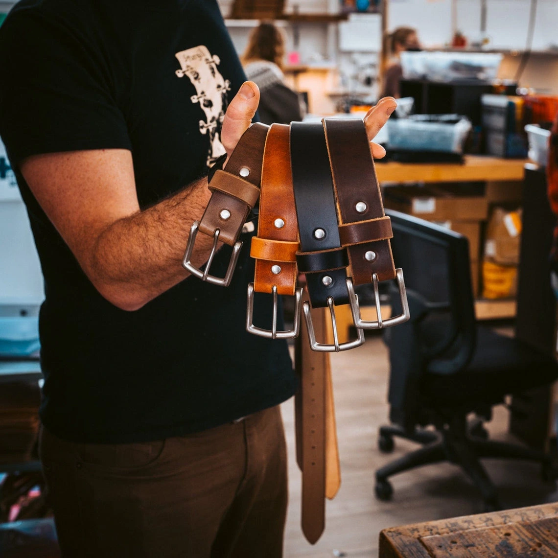 Three finished belts held up in the workshop