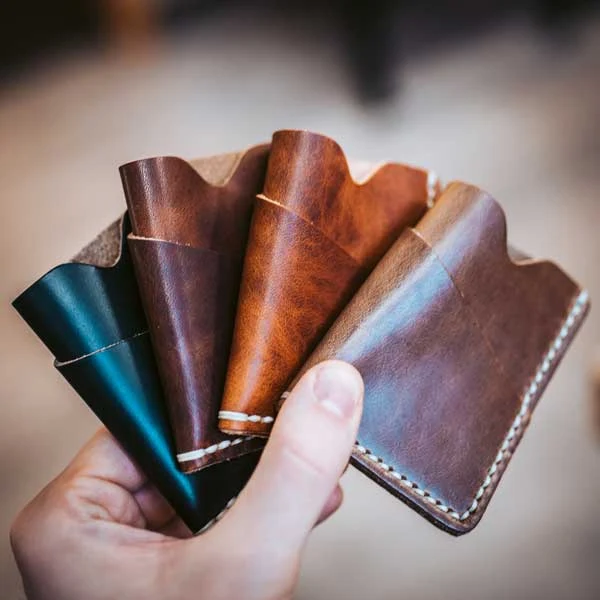 A hand fanning out card sleeves in five leather colours
