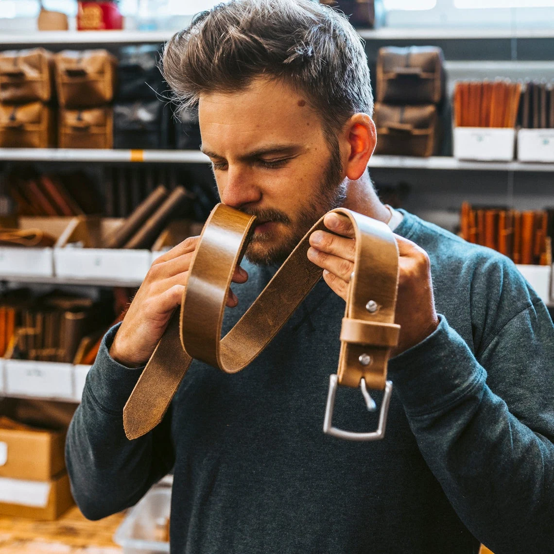 A man in the workshop smelling a new leather belt