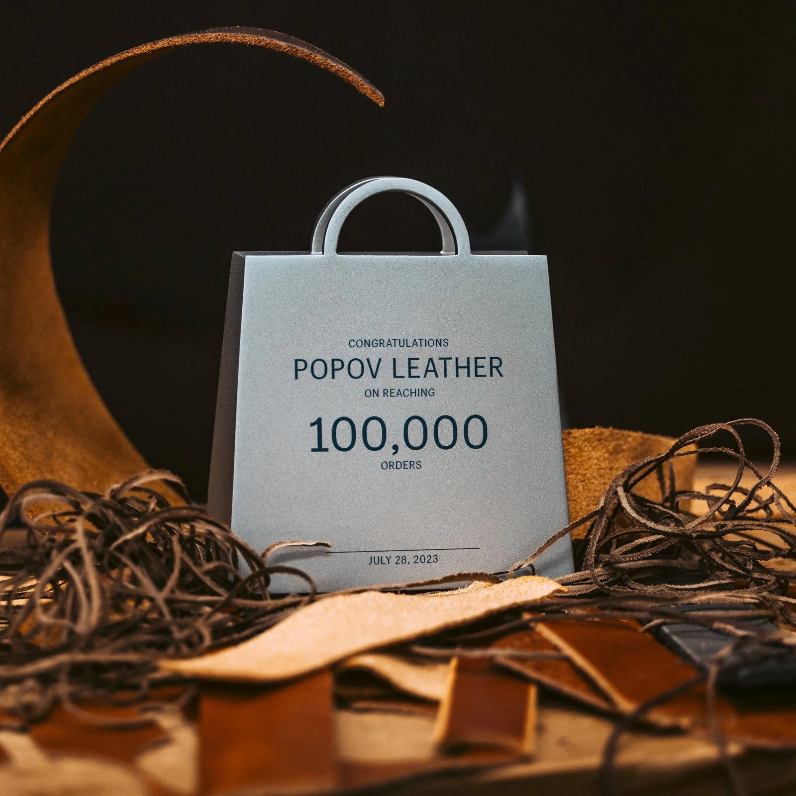 An award on the workshop bench reading Popov Leather, 100,000 orders